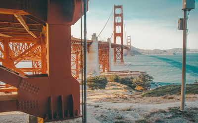 Suspension bridge over sea against sky