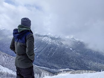 Rear view of person standing on snowcapped mountain