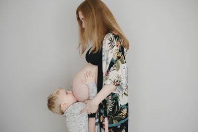 Boy kissing mothers belly