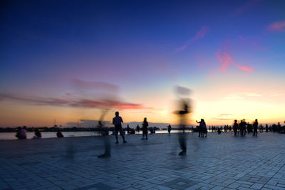 Silhouette people walking on orange sky during sunset