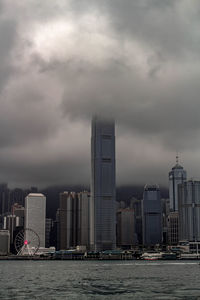 Modern buildings by river against sky in city