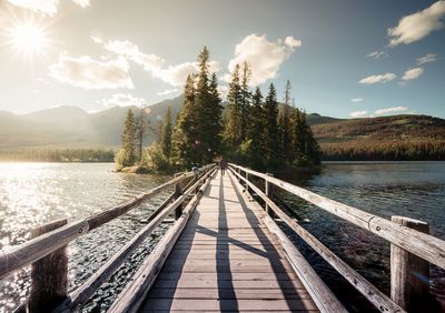 Man walking footbridge over river against trees