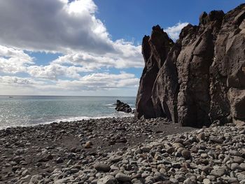 Rock formation on beach against sky