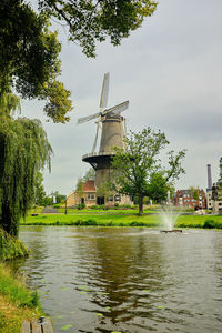 Traditional windmill by trees against sky