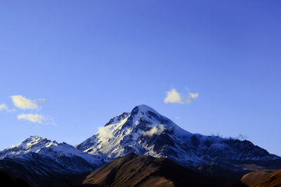 Scenic view of snowcapped mountains against blue sky