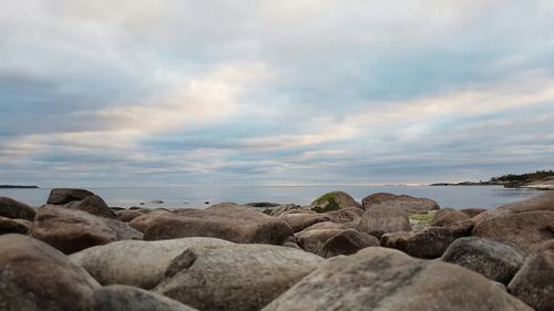 View of rocky beach against cloudy sky