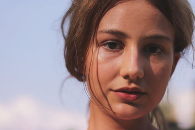 Close-up portrait of young woman against sky