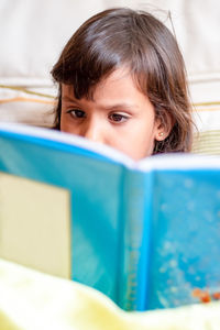 Close-up of girl reading blue book