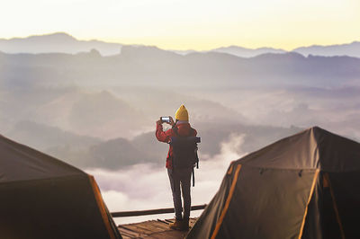 Man standing on mountain against sky during sunset