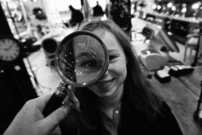 Happy woman seen through magnifying glass in shop