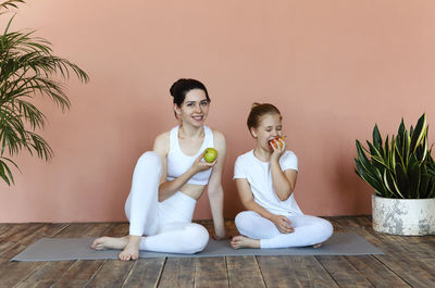 Women sitting on wooden floor against wall