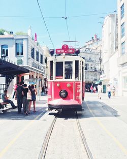 Cable car moving on tramway amidst buildings on sunny day