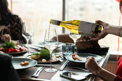 Festive lunch at the restaurant - waiter pours wine in a glass