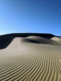 Scenic view of desert against clear blue sky