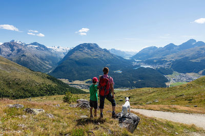 Rear view of people with dog on mountain against sky