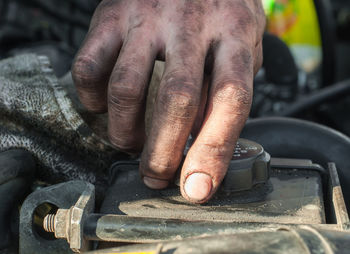 Cropped hand of mechanic opening lid in car engine