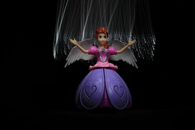 Woman with arms outstretched against black background