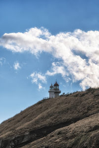 Low angle view of lighthouse by building against sky
