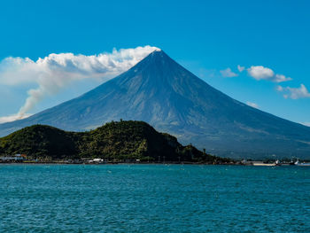 Scenic view of sea and mountains against blue sky