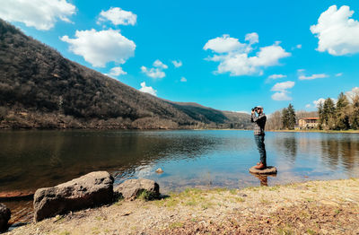 Man standing by lake against sky