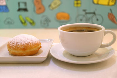 Closed up hot coffee in a white cup with blurred colorful wall paper in background