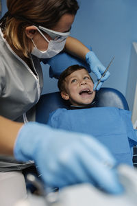 Dentist operating boy in medical clinic