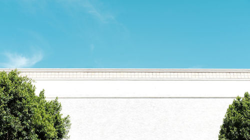 Low angle view of wall and trees against sky