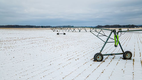 Snow covers the landscape with agricultural equipment left out