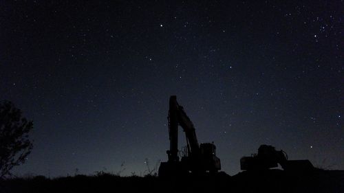 Low angle view of heavy machinery against sky at night