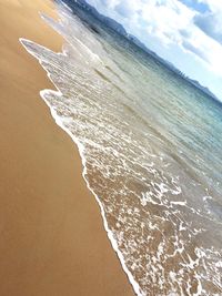 Close-up of wave on beach against sky