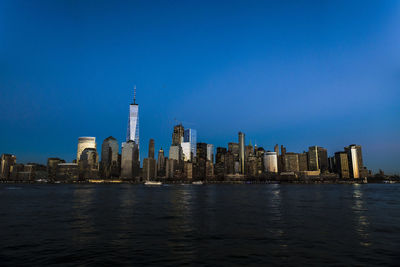 City at waterfront against blue sky