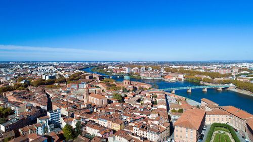 Aerial view of houses in town against blue sky