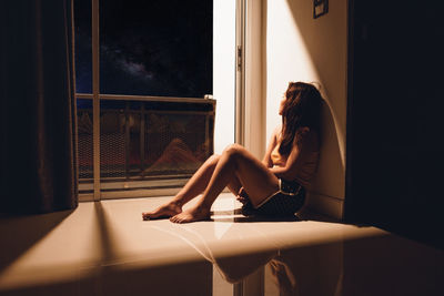 Woman sitting by window at home