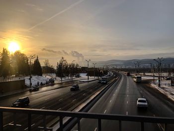 Vehicles on road against sky during sunset