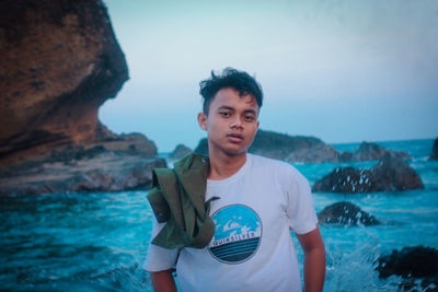 Portrait of young man standing against sea