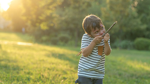 Mischief boy playing with stick at park