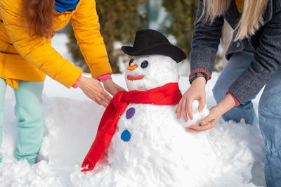 Midsection of people making snowman