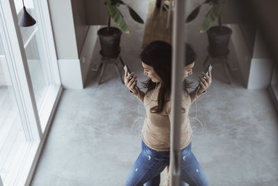 Woman listening music through in-ear headphones at home