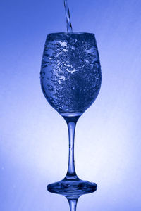 Close-up of wineglass against blue background