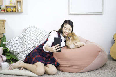 Pet lover concept. a girl is selfie with a pommerenian dog on a bed in a white living room.