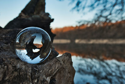 Close-up of crystal ball on rock against sky
