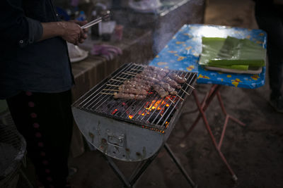 Midsection of man preparing meat on barbecue grill