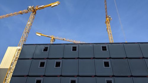 Low angle view of crane at construction site against sky