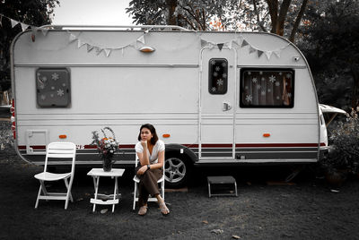 Full length portrait of woman sitting against bus