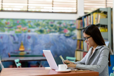 Woman using phone while sitting on table