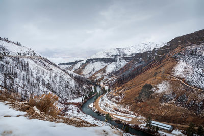 Aerial view of river flowing amidst snowcapped mountains