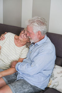 Side view of mother and daughter sitting on sofa at home