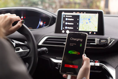 Midsection of man using smart phone in car