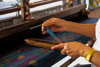 Midsection of worker preparing needle at handloom factory
