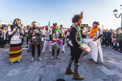 Group of people standing on street in city against sky